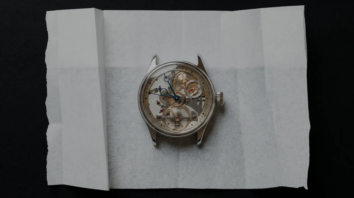 A Garrick case, the movement in view, laid on folded tissue paper in low light
